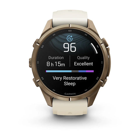 A Garmin smartwatch with a round bronze-toned metal case and a light cream-colored silicone strap, shown on a clean white background. The watch screen is active, displaying sleep and heart rate metrics.