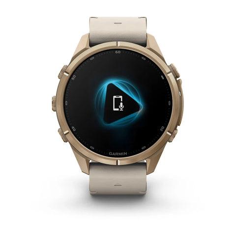 A Garmin smartwatch with a round metallic rose gold case and a light beige silicone strap, shown on a clean white background. The watch face is black with a blue and white digital display.