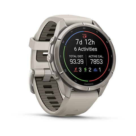 A Garmin smartwatch with a light gray silicone strap and a silver-toned metal case, shown at a three-quarter angle on a white background. The watch face is active with various fitness metrics and colorful activity indicators.