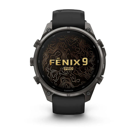 A Garmin Fenix 9 Pro smartwatch with a dark gray metallic case, black strap, and a black watch face featuring gold topographic contour lines and the text 'FENIX 9 PRO'.