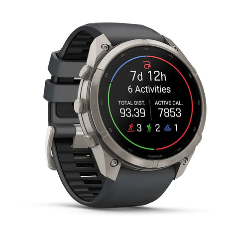 A Garmin smartwatch with a round silver-tone case and a dark gray silicone strap, shown at a three-quarter angle on a clean white background. The watch face displays fitness metrics.