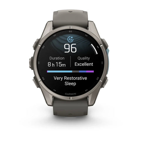 A Garmin smartwatch with a dark gray silicone strap and a metallic gunmetal gray case, shown on a clean white background. The watch face is active, displaying sleep and heart rate metrics.