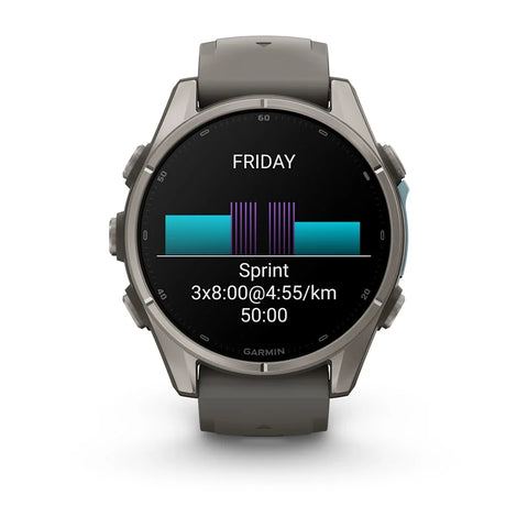 A Garmin smartwatch with a dark gray metallic case and a matching dark gray silicone strap, shown against a plain white background. The watch face is on and displaying a fitness screen with a running split and a bar chart.