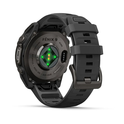 A rugged black smartwatch with a matching black silicone strap, shown from a three-quarters angle. The back of the watch face features a circular sensor area with green illuminated LED lights and the text 'FENIX 9'.