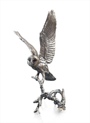 Silver owl sculpture on a branch against a white background
