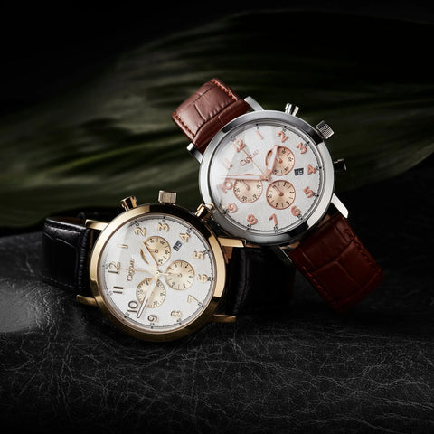 Two watches with brown leather straps on a dark textured surface