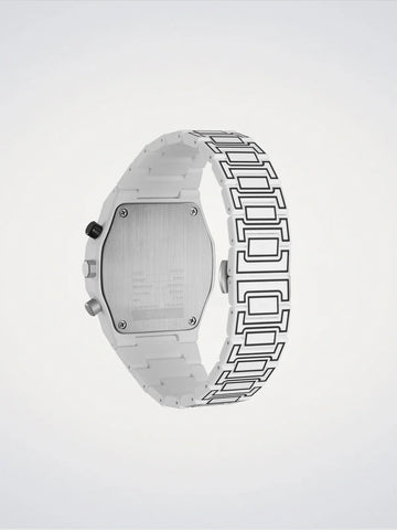 The back view of a silver-toned watch with a distinctive geometric link bracelet, shown against a light gray gradient background.