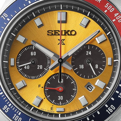 Close-up of a Seiko watch with a gold face and blue and red accents.