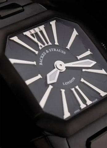 Black watch with white Roman numerals and 'Backes & Strauss London' branding.