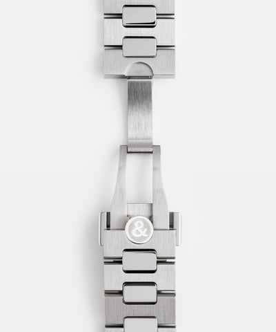 Close-up of a silver watch strap with a brand logo on a white background