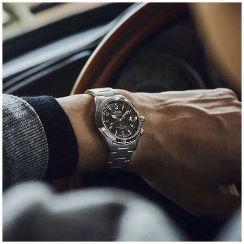 Person wearing a silver watch with a blurred car interior background
