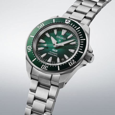 Seiko watch with green dial and silver metal bracelet on a light gray background