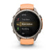 A Garmin smartwatch with a round silver-tone case and an orange strap, shown on a clean white background. The watch screen displays fitness activity options including MTB, Trail Run, Row Indoor, Rucking, and Ski.
