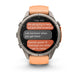 A Garmin smartwatch with a round silver-toned metal case and a peach-orange silicone strap, shown on a clean white background. The watch face displays a messaging app screen.