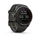 A Garmin smartwatch with a black round case and a textured black strap, shown at a three-quarter angle on a clean white background. The digital display is active, showing fitness metrics.