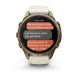 A Garmin smartwatch with a round bronze-toned case and a light beige silicone strap, shown on a clean white background. The watch face displays a messaging app screen.