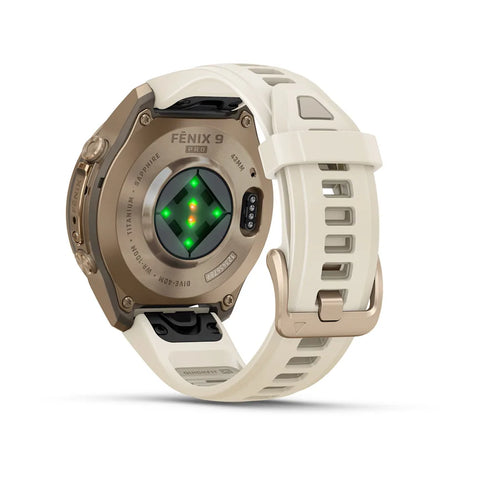 A Fénix 9 GTS smartwatch shown from the back, featuring a metallic bronze case, a light beige silicone strap, and a central green LED light indicator, set against a clean white background.