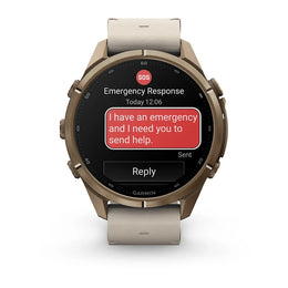 A Garmin smartwatch with a bronze-toned metal case and a light beige strap, shown on a clean white background. The watch screen displays an emergency message with a red SOS icon and a red text bubble reading, 'I have an emergency and I need you to send he