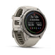 A Garmin smartwatch with a light gray silicone strap and a silver-toned metal case, shown at a three-quarter angle on a white background. The watch face is active with various fitness metrics and colorful activity indicators.