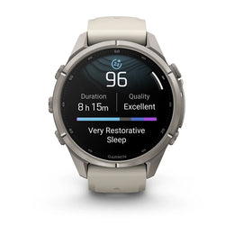 A Garmin smartwatch with a round silver titanium case and a light beige silicone strap, shown on a clean white background. The watch face is active, displaying sleep and fitness metrics.