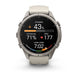 A Garmin smartwatch with a round silver stainless steel case and a light beige silicone strap, shown on a clean white background. The watch face is active with various fitness and heart rate metrics displayed.
