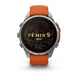 A Garmin Fenix 9 Pro smartwatch with a round silver-toned metal case, an orange leather strap, and a black watch face featuring gold topographic contour lines and the text 'FENIX 9 PRO'.