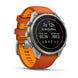 A Garmin smartwatch with a round silver stainless steel case and an orange and orange-yellow silicone strap, shown on a clean white background with a soft shadow.
