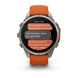 A Garmin smartwatch with a silver-toned metal case and an orange strap, shown on a clean white background. The watch face displays a messaging app interface.
