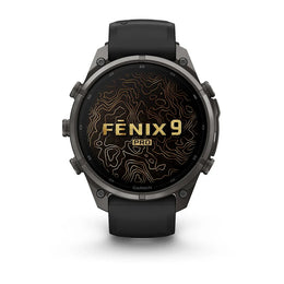 A Garmin Fenix 9 Pro smartwatch with a dark gray metallic case, black strap, and a black watch face featuring gold topographic contour lines and the text 'FENIX 9 PRO'.