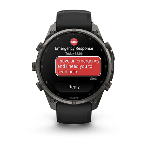 A rugged black Garmin smartwatch with a dark metallic case and black strap, shown on a clean white background. The watch screen displays an emergency message app with a red SOS badge and a red text bubble reading 'I have an emergency and I need you to sen
