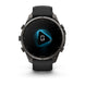 A Garmin smartwatch with a dark gray metallic case and a black strap, shown from the front on a clean white background. The watch face displays a black screen with a glowing blue geometric icon.