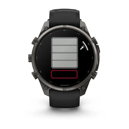 A Garmin smartwatch with a dark gray metallic case and a black strap, shown from the front on a white background. The watch face displays a digital battery indicator graphic with gray and red sections.
