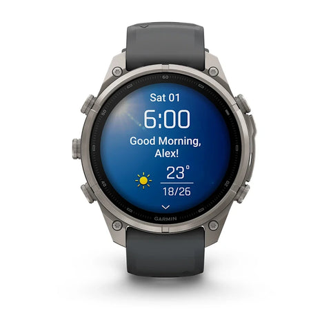A Garmin smartwatch with a round silver-tone metal case and a dark gray silicone strap, shown on a clean white background. The watch face is illuminated with a blue digital display showing the time and weather.