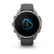 A Garmin smartwatch with a round silver-toned metal case and a dark gray silicone strap, shown against a plain white background. The watch face displays a black screen with a glowing blue geometric icon.