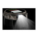 A rugged smartwatch shown in side profile with a bright built-in LED light turned on, casting a strong beam of white light forward against a black background.