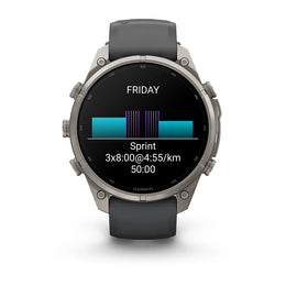 A Garmin smartwatch with a dark gray strap and a silver-toned metal case, shown against a plain white background. The watch face is on and displays a fitness screen with a purple and teal bar graph and the text 'FRIDAY', 'Sprint', and '3x8:00@4:55/km 50:0
