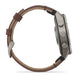 A side profile view of a rugged smartwatch with a brown leather strap and a metallic gray case, set against a plain white background.