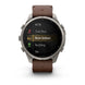 A Garmin smartwatch with a brown leather strap and a silver-toned metal case, shown on a clean white background. The watch face displays a fitness menu with options like MTB, Trail Run, Row Indoor, Rucking, and Ski.