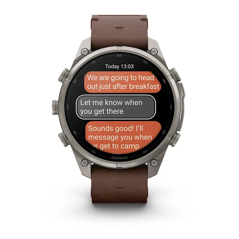 A Garmin smartwatch with a brown leather strap and a silver-toned metal case, displaying a messaging app on its screen against a white background.