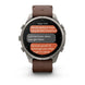 A Garmin smartwatch with a brown leather strap and a silver-toned metal case, displaying a messaging app on its screen against a white background.