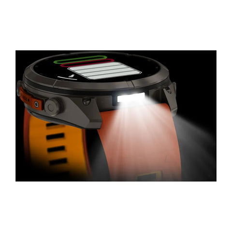A rugged smartwatch with a dark gray case and an orange strap, shown with a bright built-in flashlight illuminated on a black background.