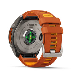 A rugged smartwatch shown from the back on a clean white background, featuring an orange silicone strap with yellow accents, a silver titanium case, and a green heart-rate sensor on the back.