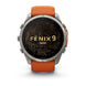 A Garmin Fenix 9 Pro smartwatch with a round silver-toned metal case, a black display screen featuring gold topographic lines and 'FENIX 9 PRO' text, and an orange silicone strap, shown against a plain white background.