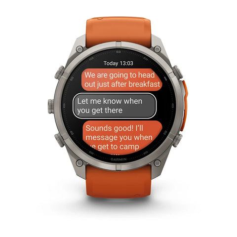 A Garmin smartwatch with a silver-toned metal case and an orange silicone strap, shown on a clean white background. The watch face displays a messaging app screen.