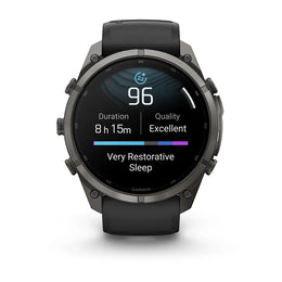 A Garmin smartwatch with a dark gray metallic case and a black strap, shown against a plain white background. The watch face is illuminated with a sleep tracking app screen.