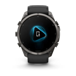 A Garmin smartwatch with a dark gray metallic case and a black strap, shown from the front on a white background. The screen displays a blue and white graphic.