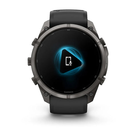 A Garmin smartwatch with a dark gray metallic case and a black strap, shown from the front on a white background. The screen displays a blue and white graphic.