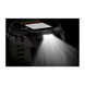 A rugged black smartwatch with a bright built-in LED light turned on, casting a strong beam of white light against a dark background.