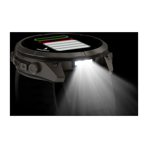 A rugged smartwatch shown at an angle with its front light turned on, emitting a bright beam of light downward against a black background.