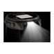 A rugged smartwatch shown at an angle with its front light turned on, emitting a bright beam of light downward against a black background.